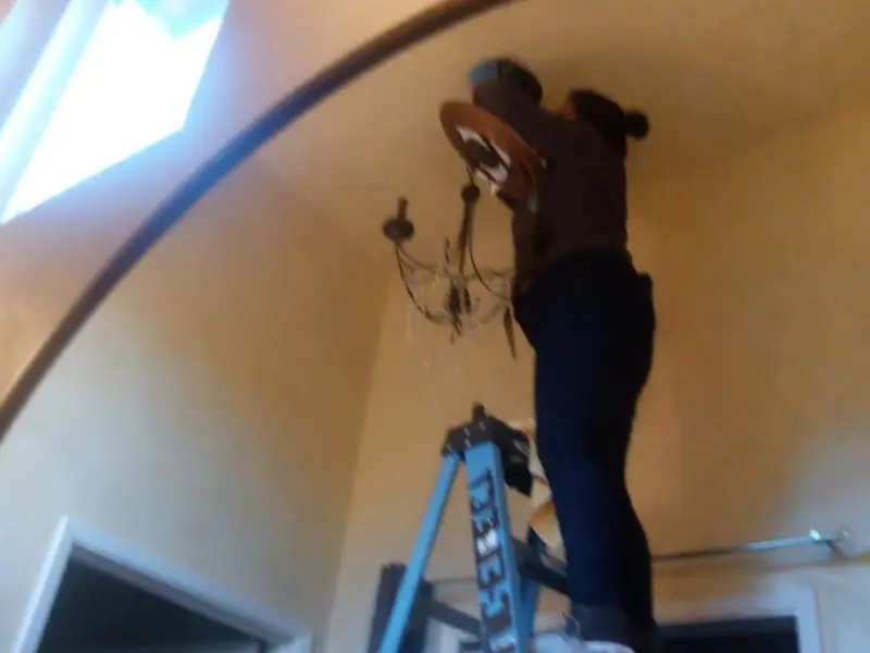 Electrician installing a chandelier in a Orchard Mesa residence
